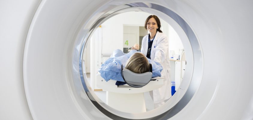 Ärztin mit Patientin vor medizintechnischem Computertomographen
